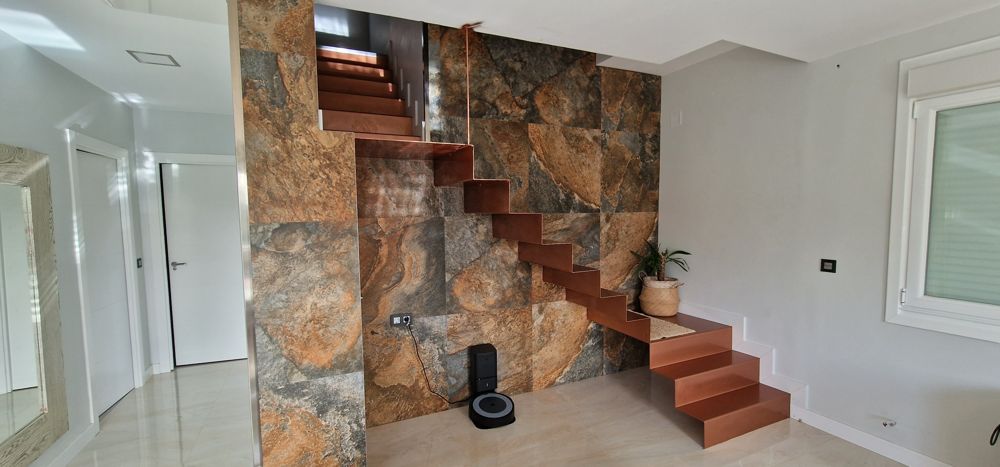 Reforma moderna con escalera y pared de piedra en Ourense